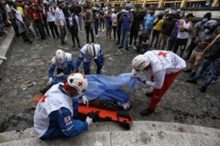 Paramédicos recogen el cuerpo de un hombre asesinado por manifestantes antigubernamentales al que acusaron de matar a un compañero manifestante que bloqueaba su paso en un control de carretera establecido por manifestantes en Cali, Colombia, el viernes 28 de mayo de 2021. (AP Foto/Andrés Gonzalez)